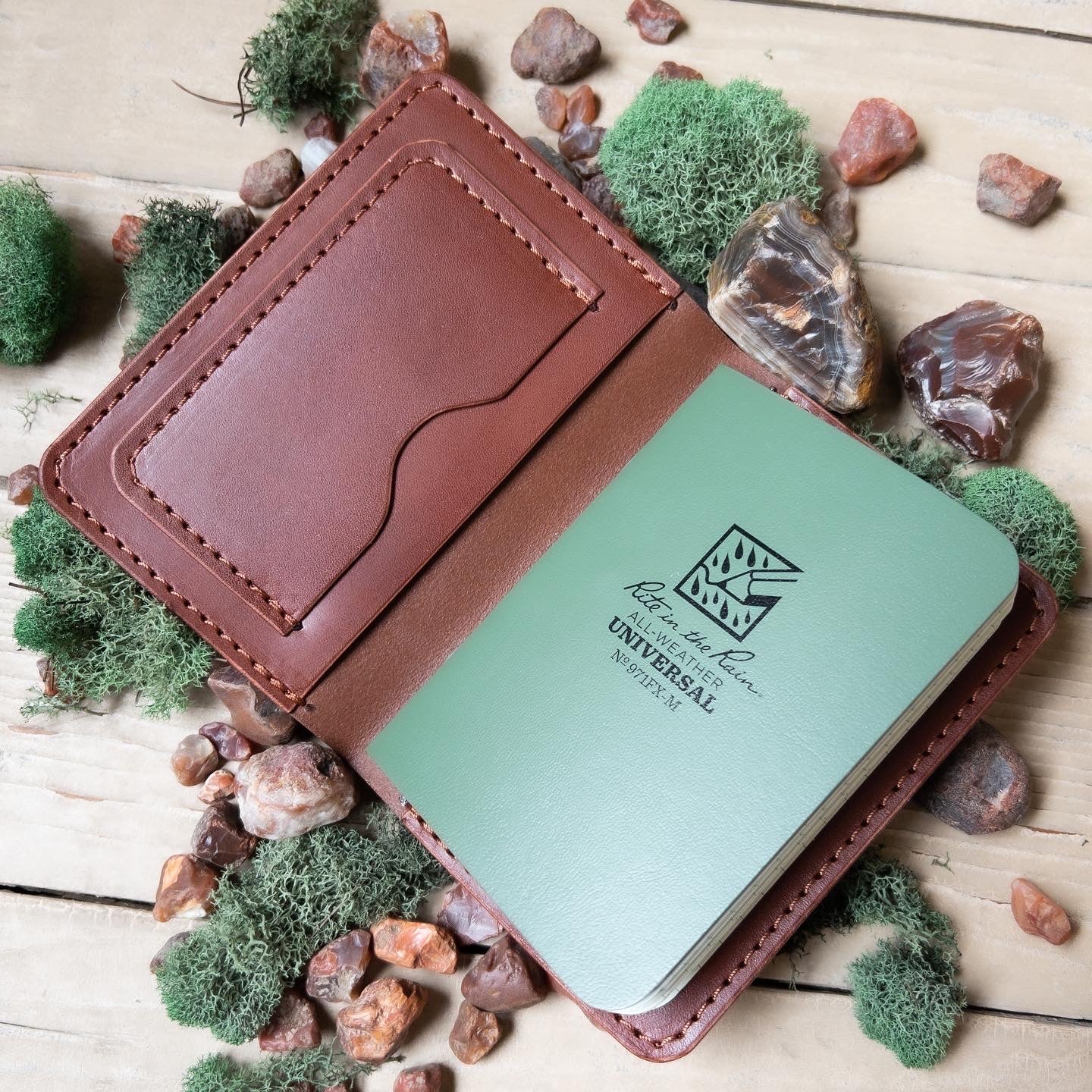 field notes journal inside handmade brown leather case surrounded by lake superior agates