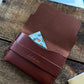 hand brown leather wallet with cash and cards in it